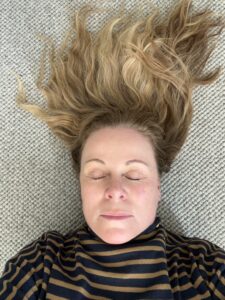 Kvinna ligger med slutna ögon på en matta i en lugn stund för meditation, mindfulness och stresshantering